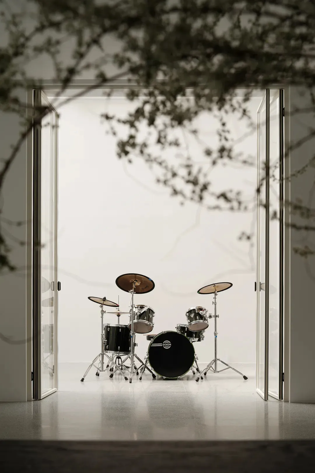 A modern drum set room with glass doors and black and silver drums.