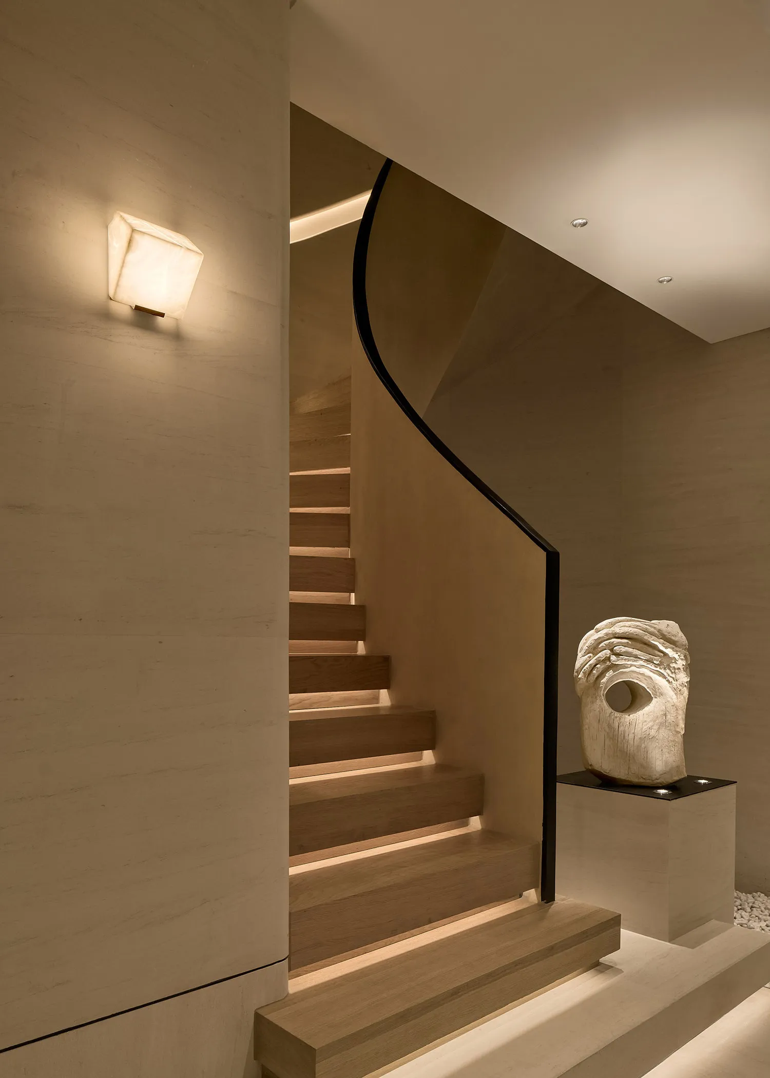 Modern interior staircase with wooden treads and a sleek, curved railing.