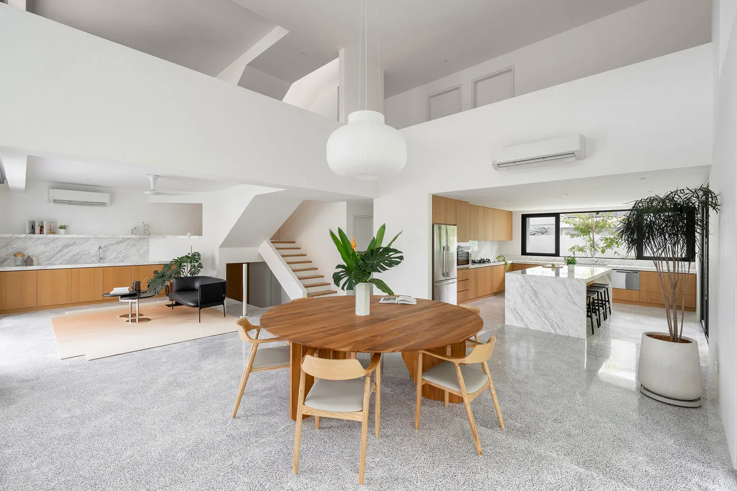 A minimalist kitchen with wooden furniture, marble countertops, and a terrazzo floor.