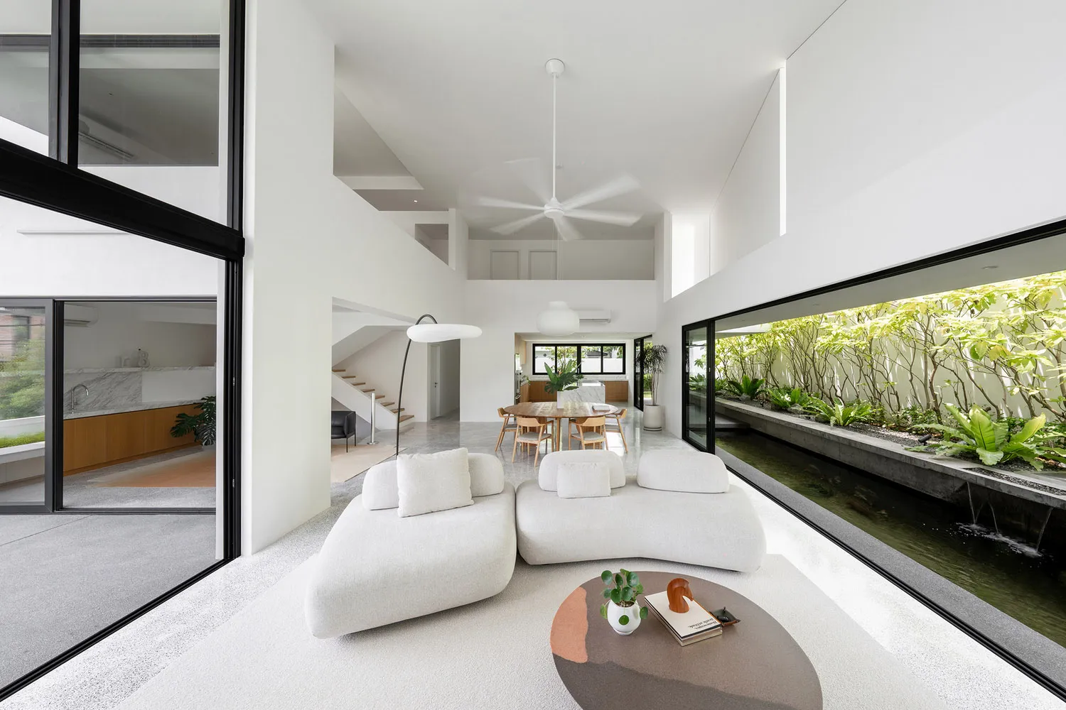 Modern minimalist living room featuring white furnishings and concrete elements.