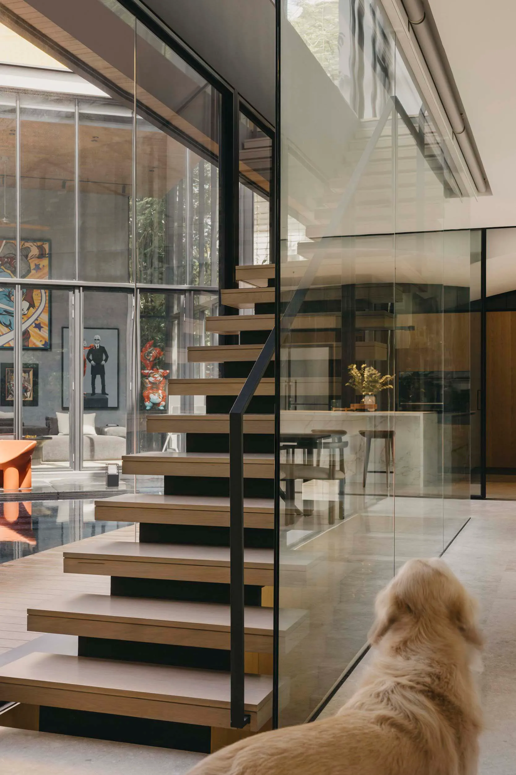 A modern minimalist staircase with glass railings in a residential living space.