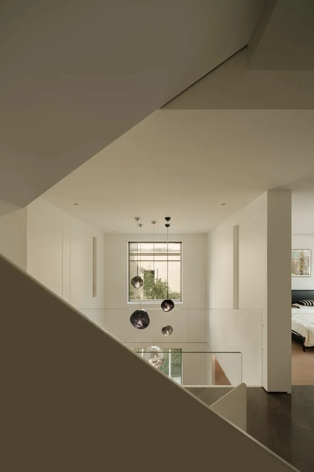 Modern minimalist residential interior with white space, glass accents, and a window view.