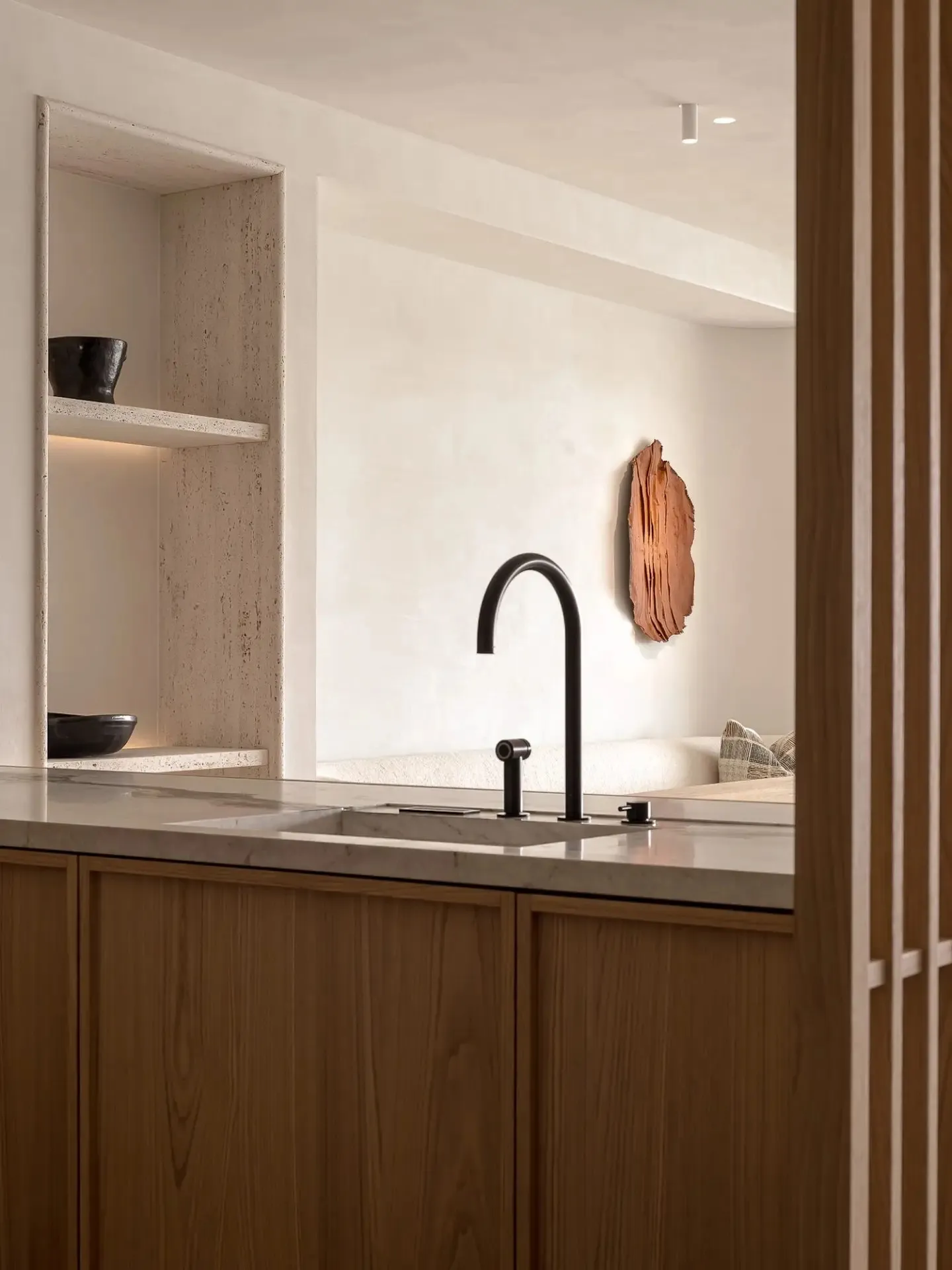Modern kitchen featuring minimalist design, stone countertops, and wooden cabinetry.