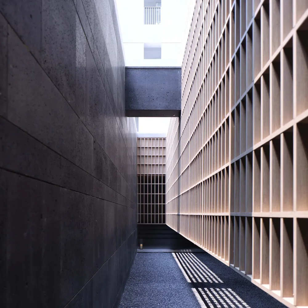 A modern lobby with concrete walls and a grid-like wooden panel system.