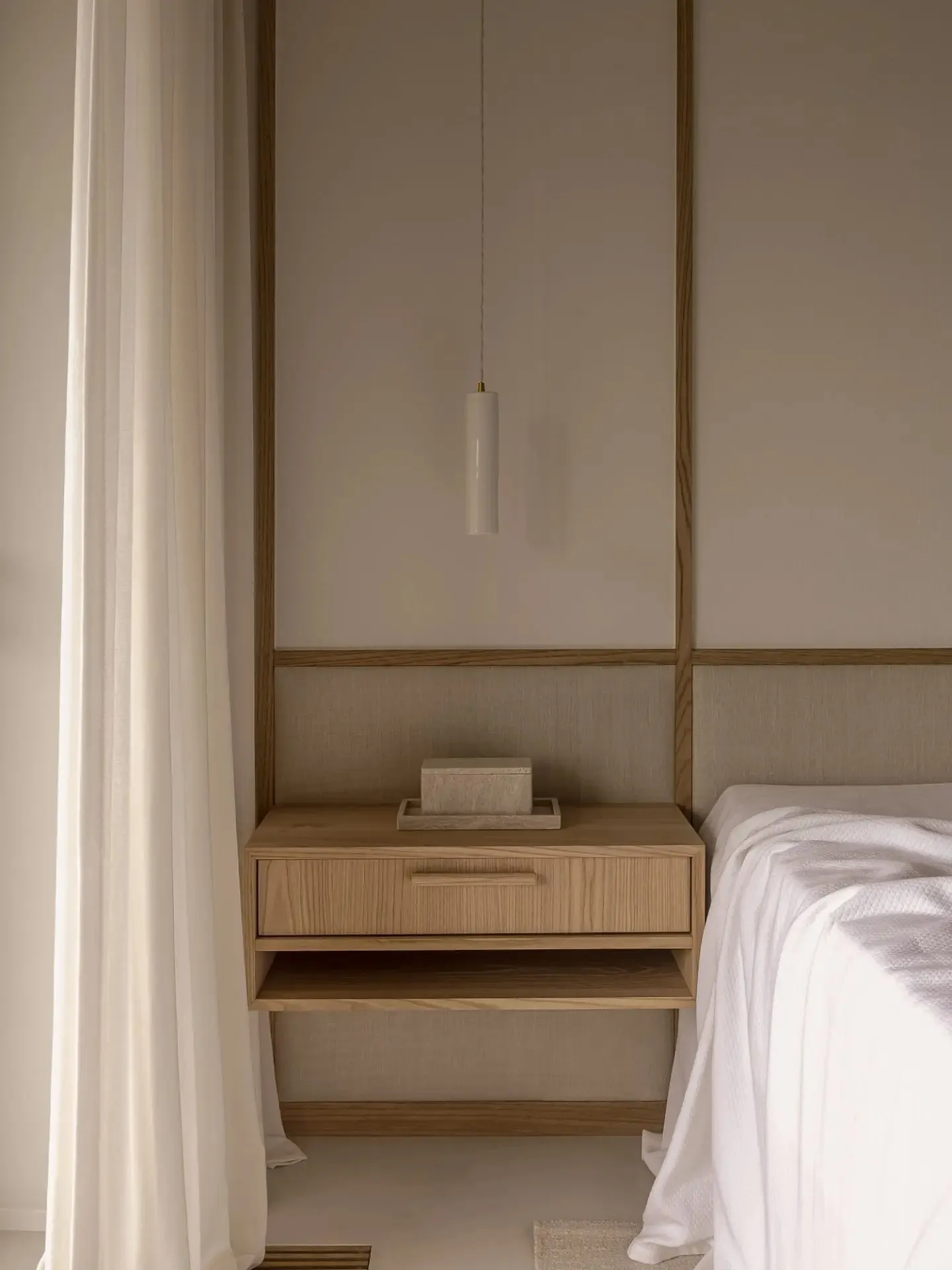 Minimalist bedroom with a floating nightstand, wooden elements, and a sleek pendant lamp.