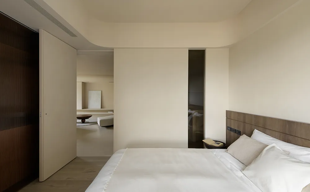 Bedroom with minimalist design featuring wooden walls and white bedding.