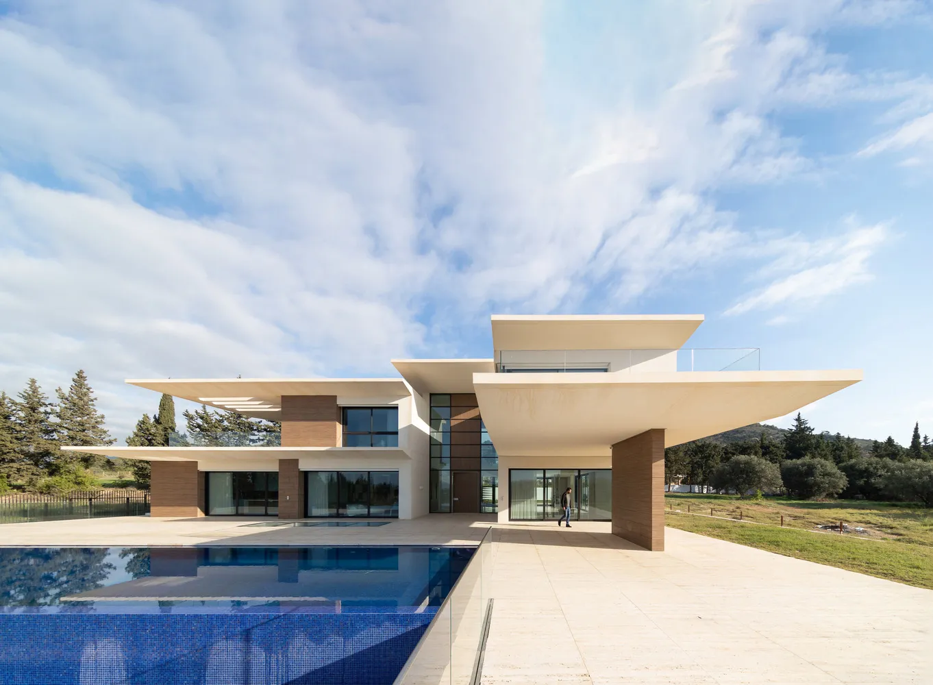 A modern house with a concrete exterior, featuring large glass windows and a pool.