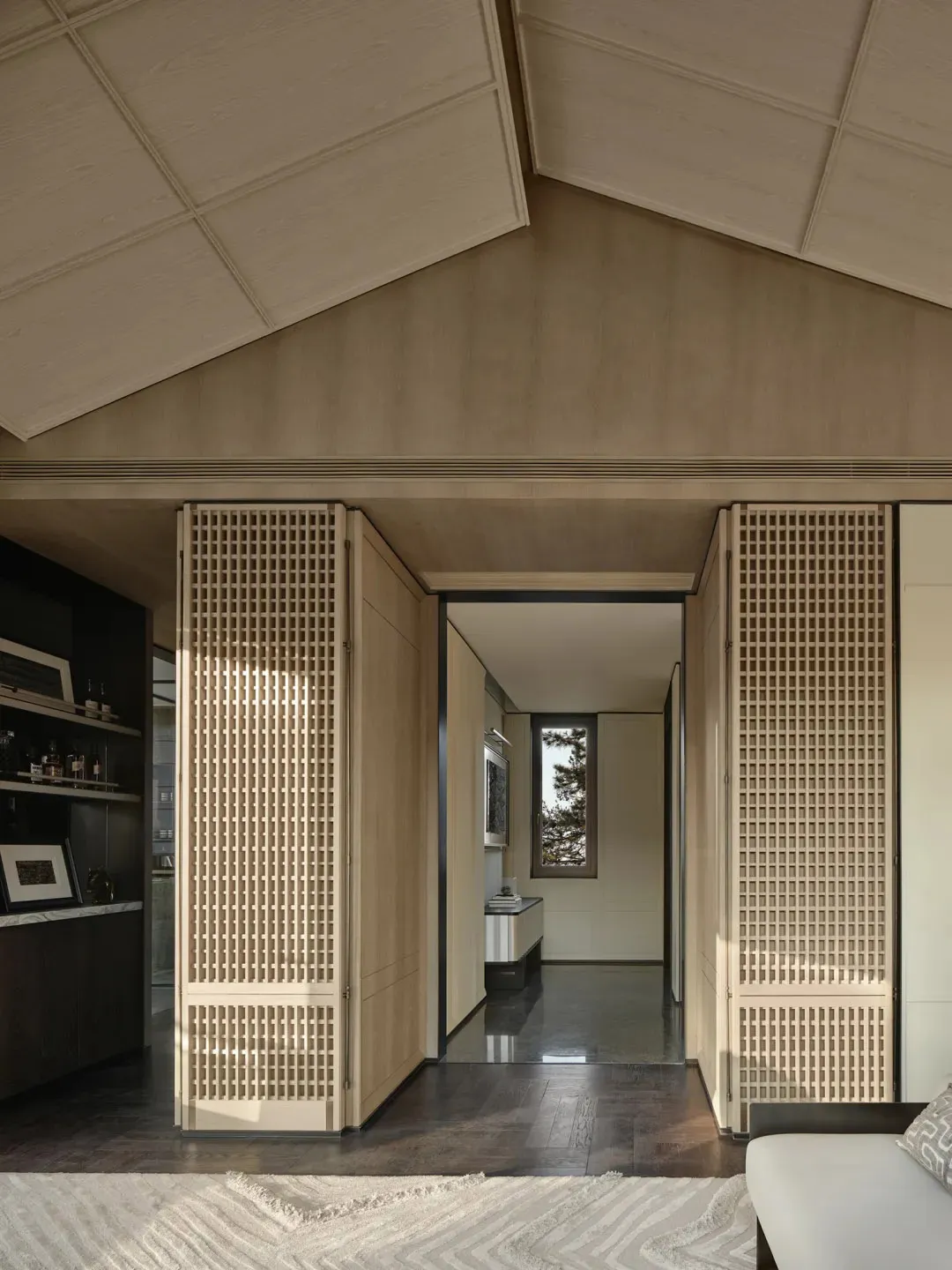 A contemporary living room featuring wooden paneling and a geometric ceiling design.