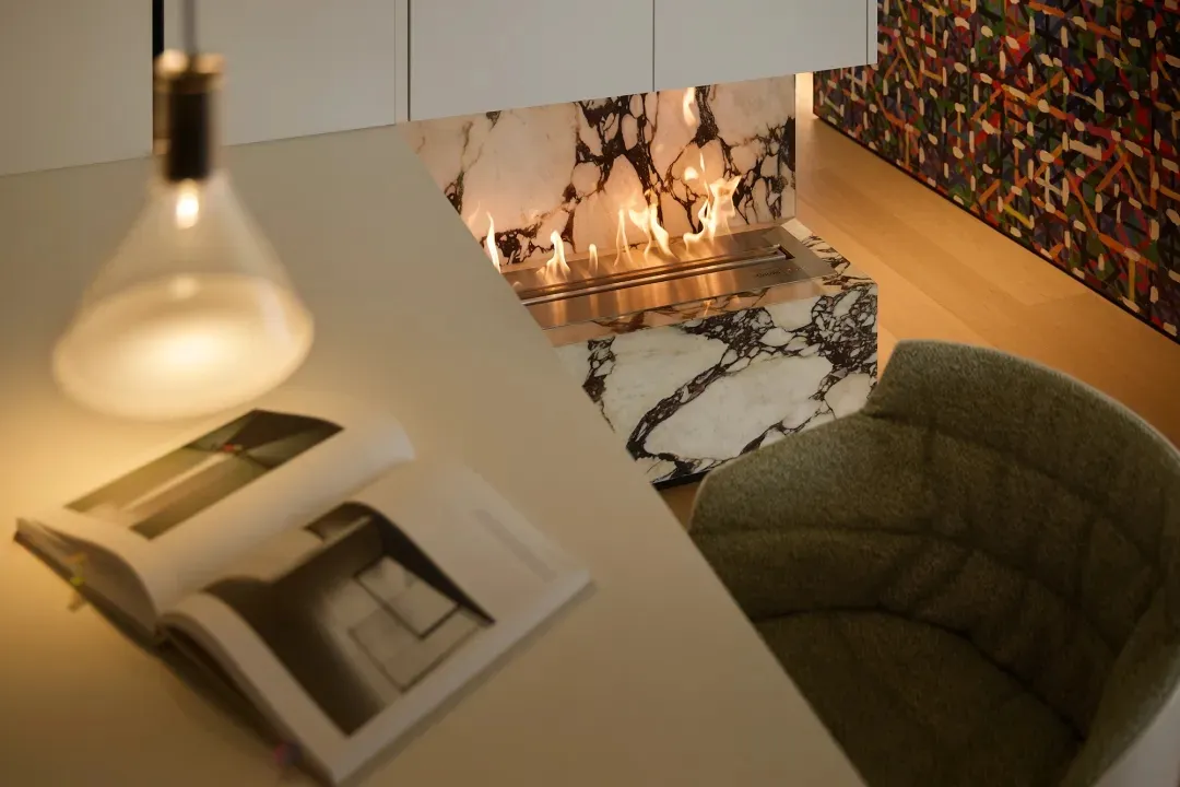 Modern living space with a marble fireplace and a plush, grey armchair.