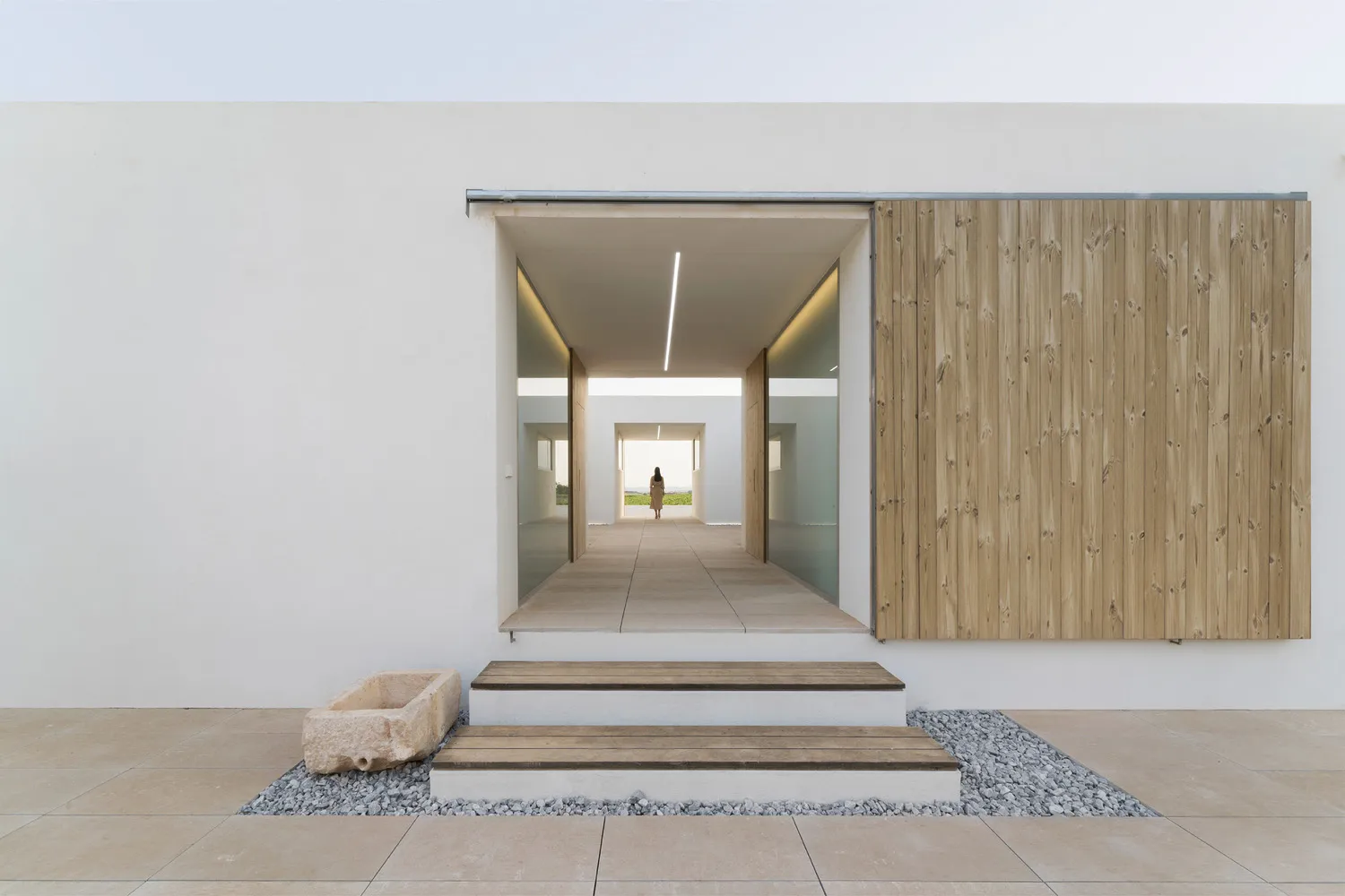 Modern minimalist entryway with concrete walls and wooden upper walls and ceiling, featuring a single light source and a pers