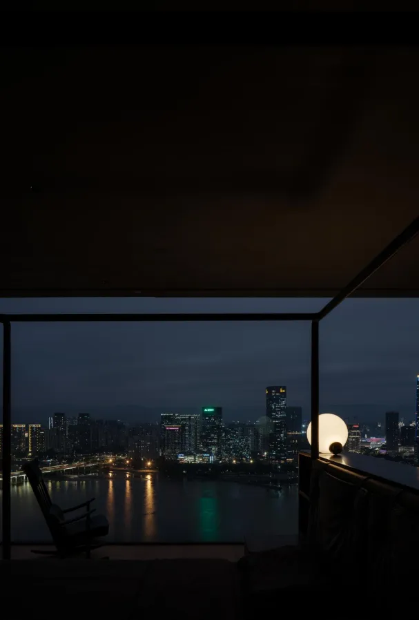 Interior night view showing a cityscape through a glass window frame.