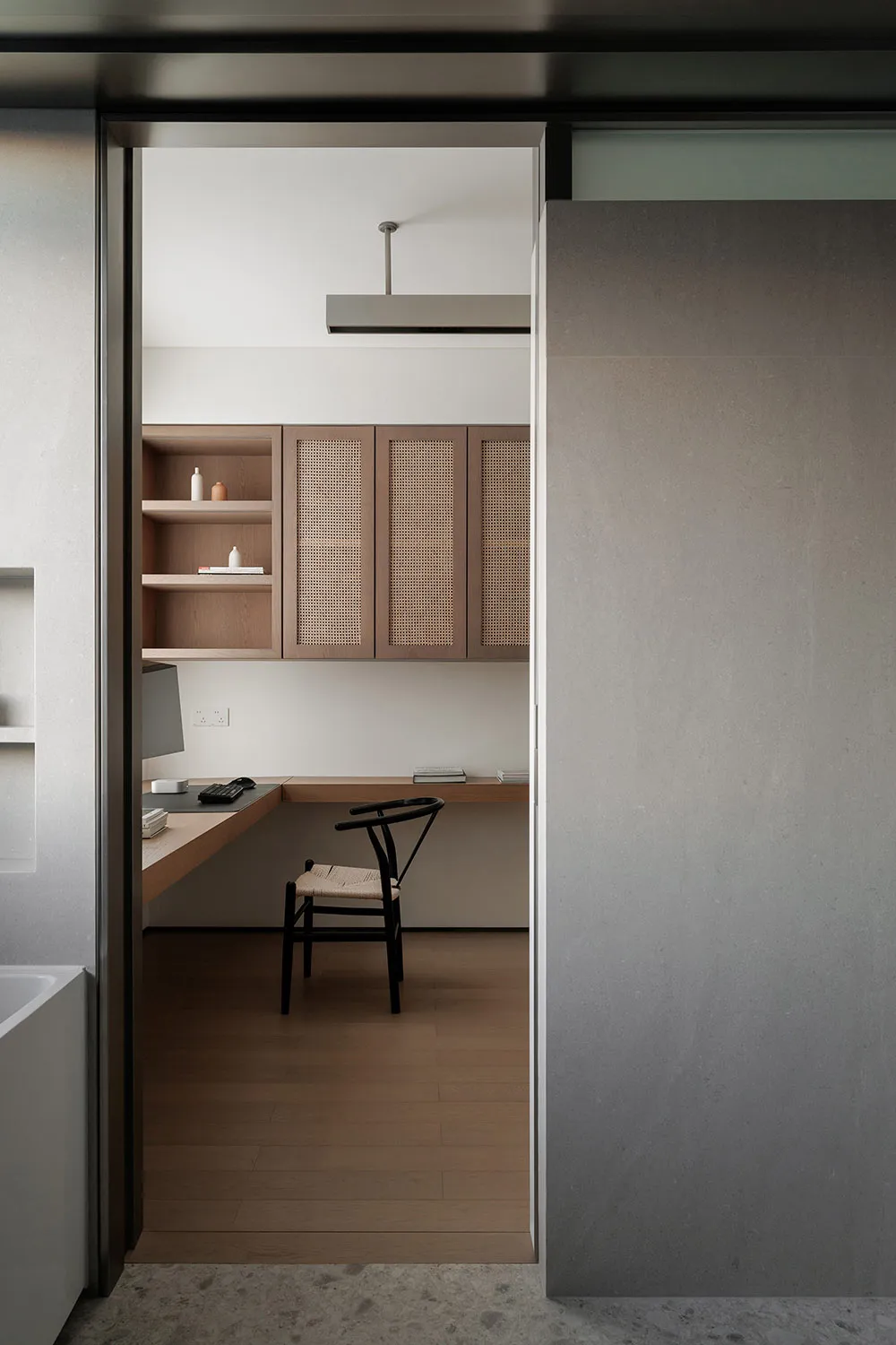 A modern minimalist home office with wooden furniture and cabinets, featuring a sleek desk and a comfortable chair.
