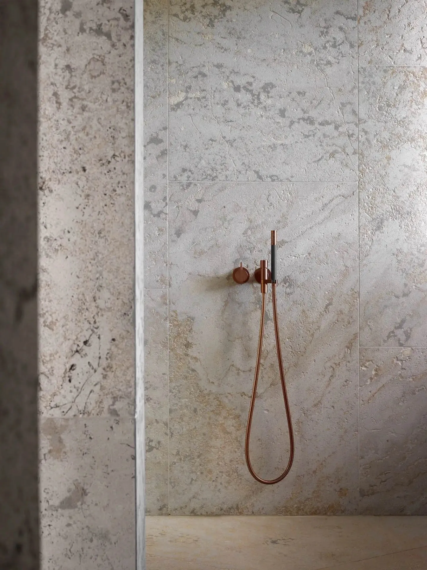 Modern bathroom with marble floor tiles, metallic shower head, and minimalist design.