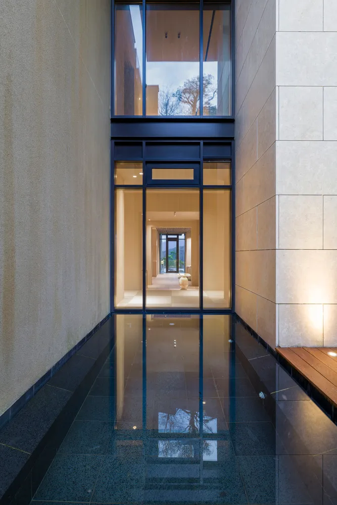 A modern hallway with large glass windows reflecting the sky and surroundings.