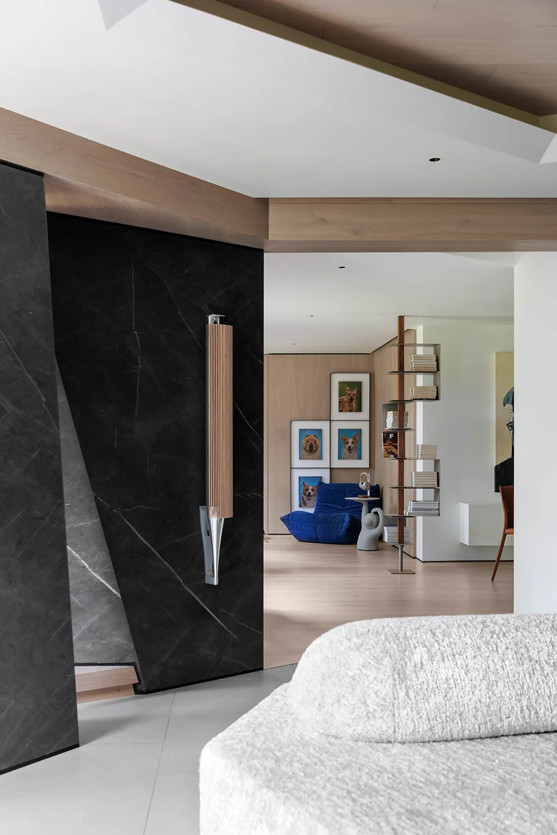 A modern living room featuring dark marble walls and wooden finishes.