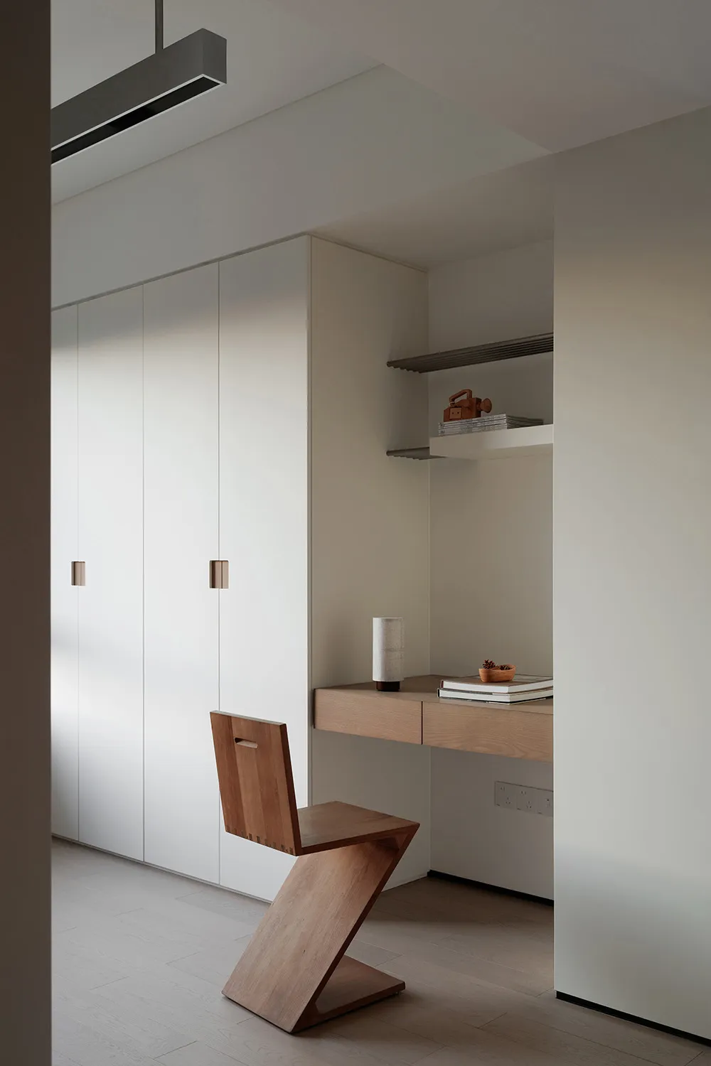 A sleek, minimalist wooden chair with a unique zigzag design, placed in a modern home office setting.