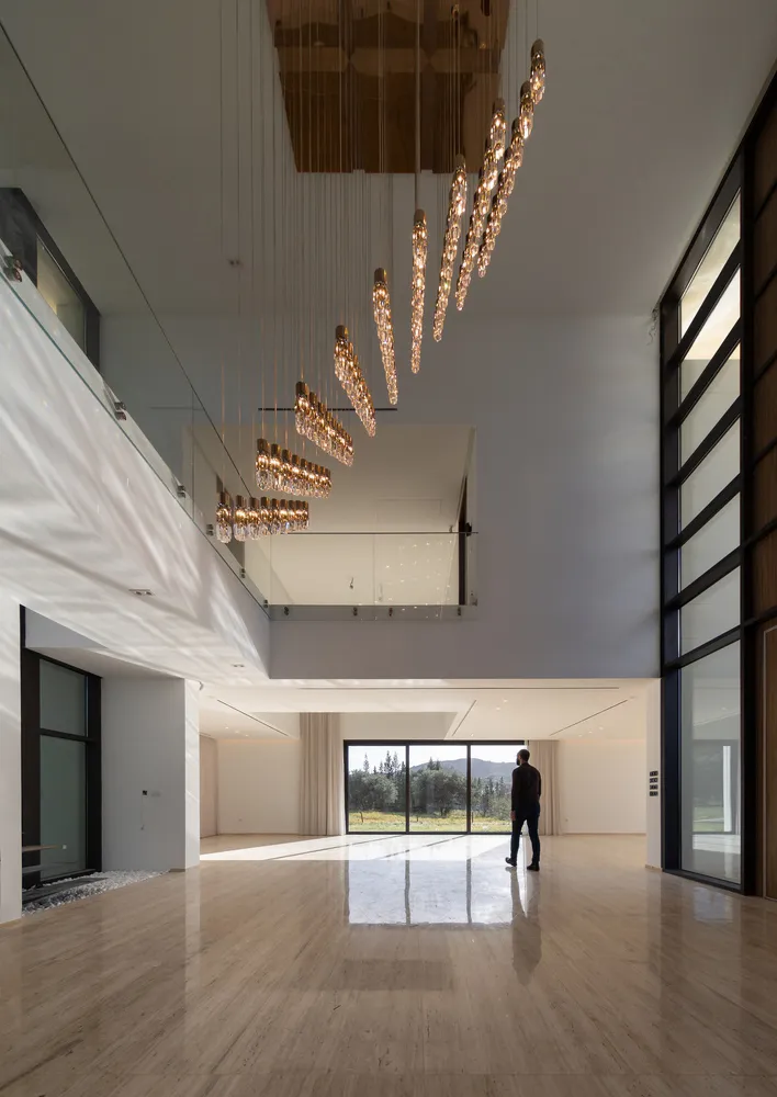 A luxurious modern residential interior featuring polished marble flooring, large glass windows, concrete walls, and contempo