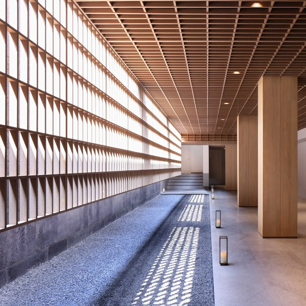A modern interior design featuring a lobby with a concrete floor, wood accents, and a wooden ceiling with visible beams.