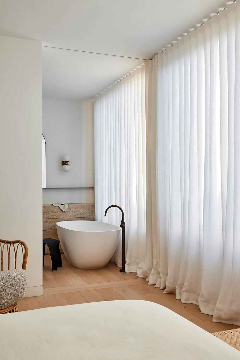 A minimalist bathroom with a white curtain and wooden floor.