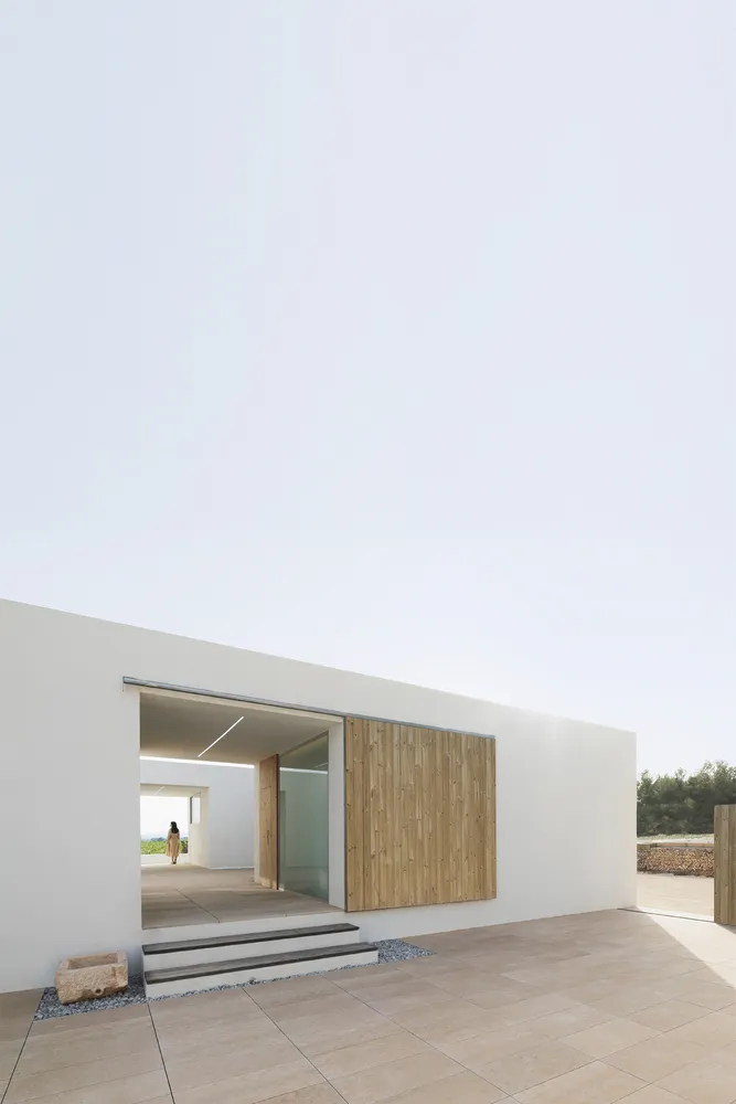 Modern minimalist exterior of a building with a concrete wall and wooden shutter.