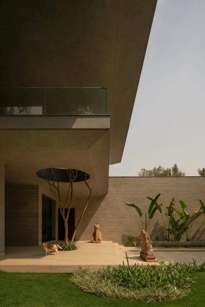 Modern architectural design featuring a concrete exterior, glass walls, and greenery in a garden setting.