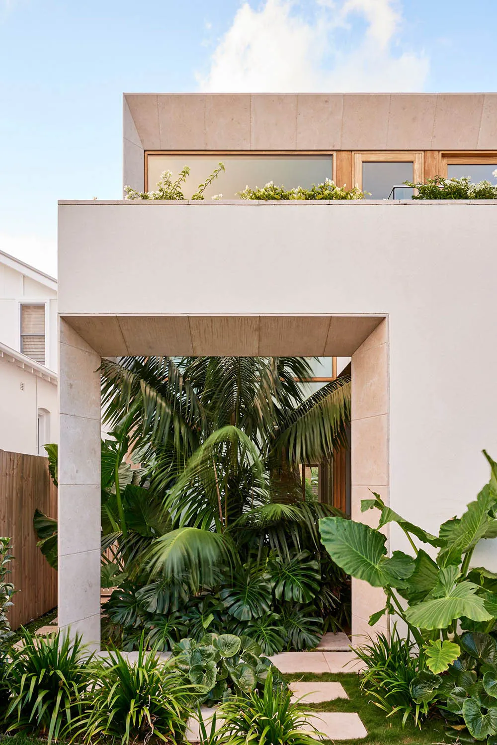 A modern house with a concrete facade and lush greenery in the garden.