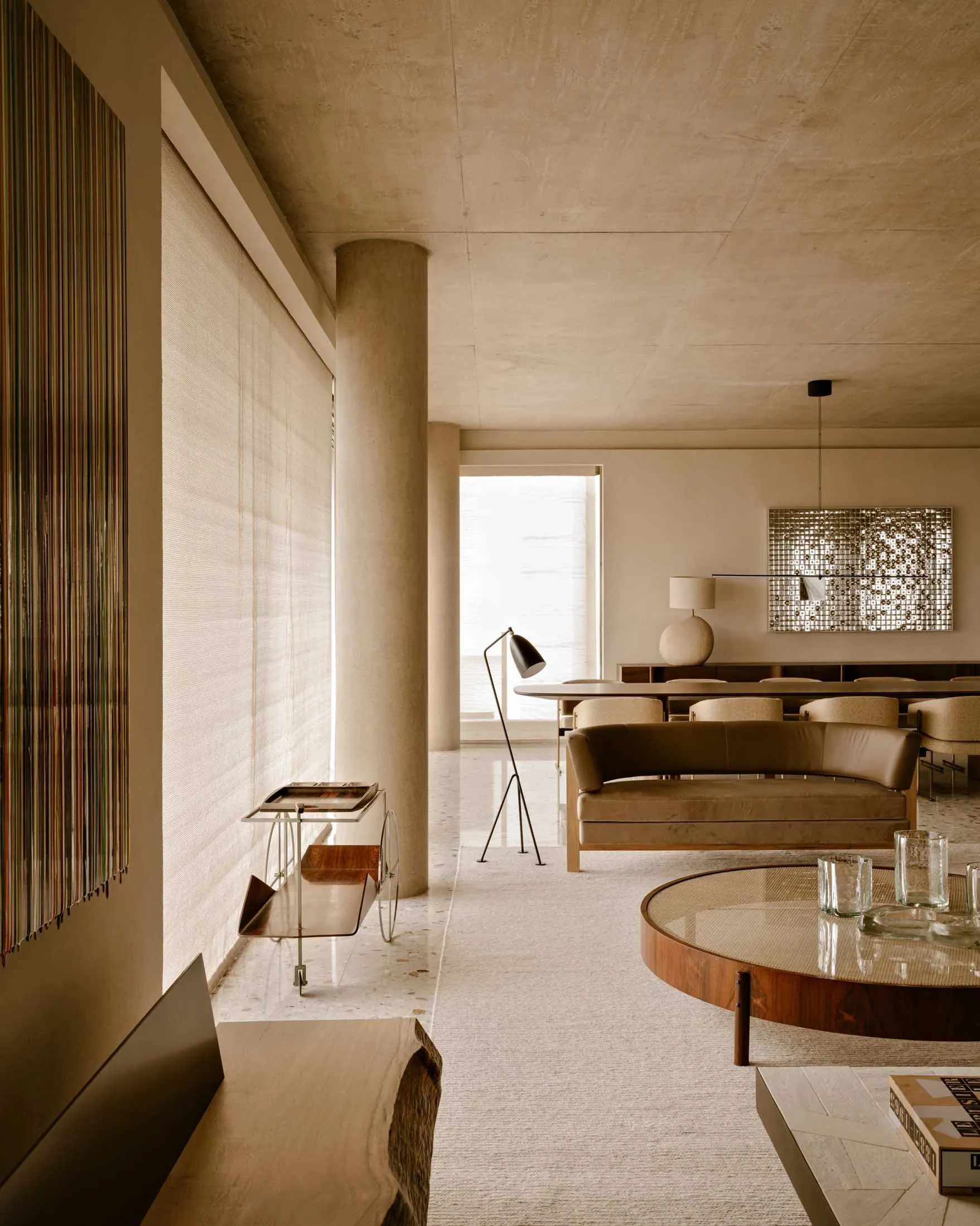 A modern interior design living room featuring a concrete wall and floor, minimalist furniture, and a sleek coffee table.