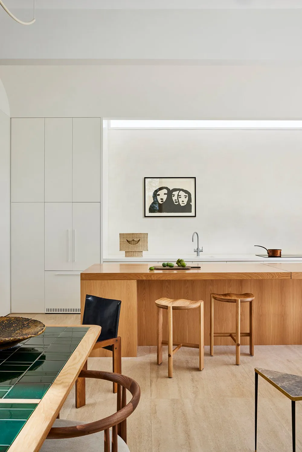 A modern kitchen featuring marble countertops and wooden stools.