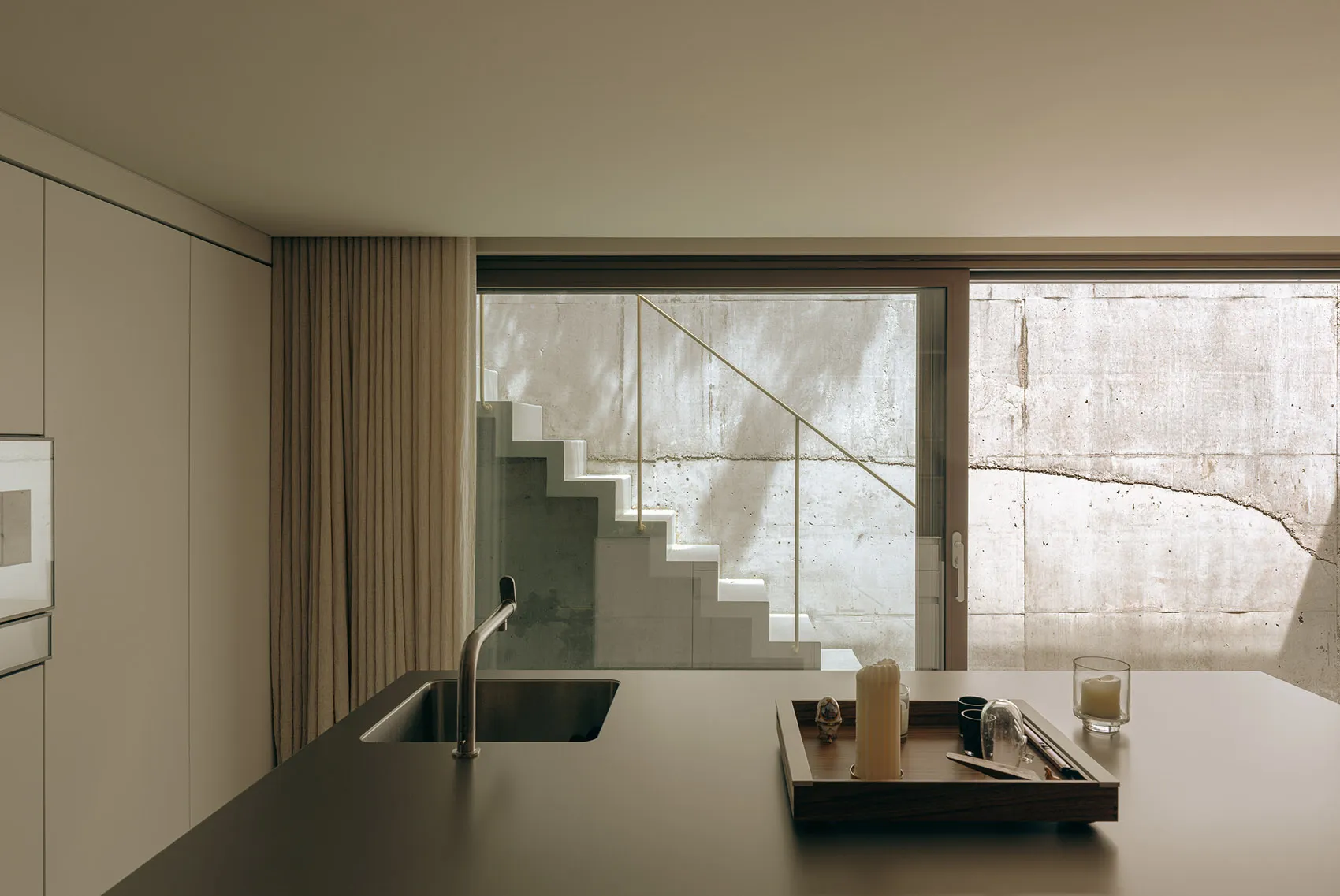A modern, minimalist residential kitchen featuring concrete elements.