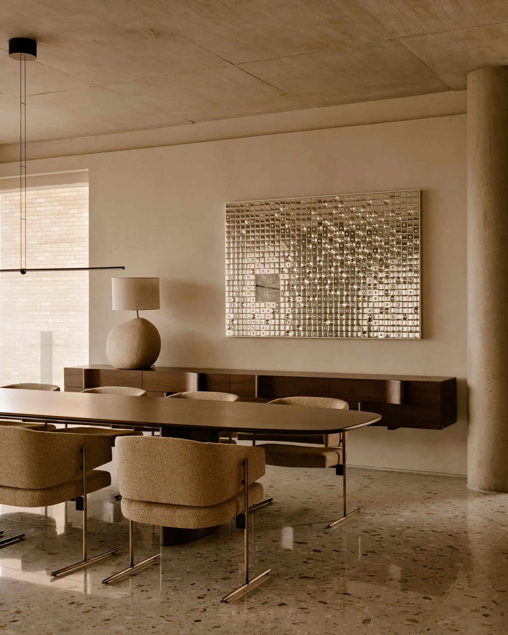 Modern dining room featuring a metallic art piece and wooden dining table.