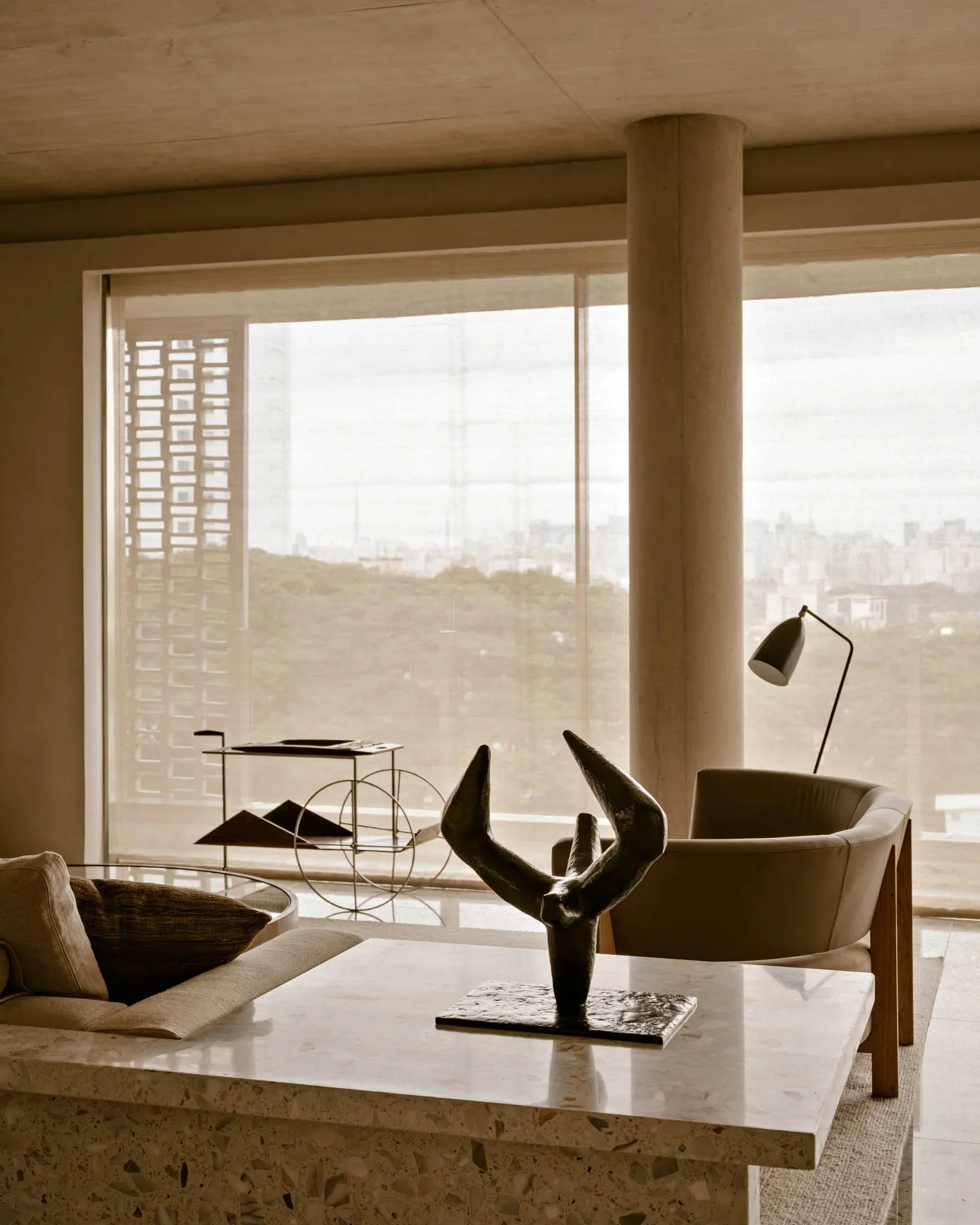 Modern living room with terrazzo countertop and minimalist decor, featuring a sculpture on a table.