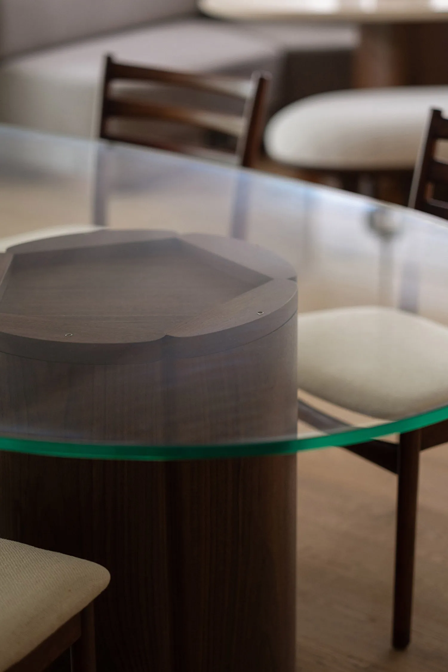 Close-up of a modern minimalist interior featuring a sleek glass dining table with wooden base.