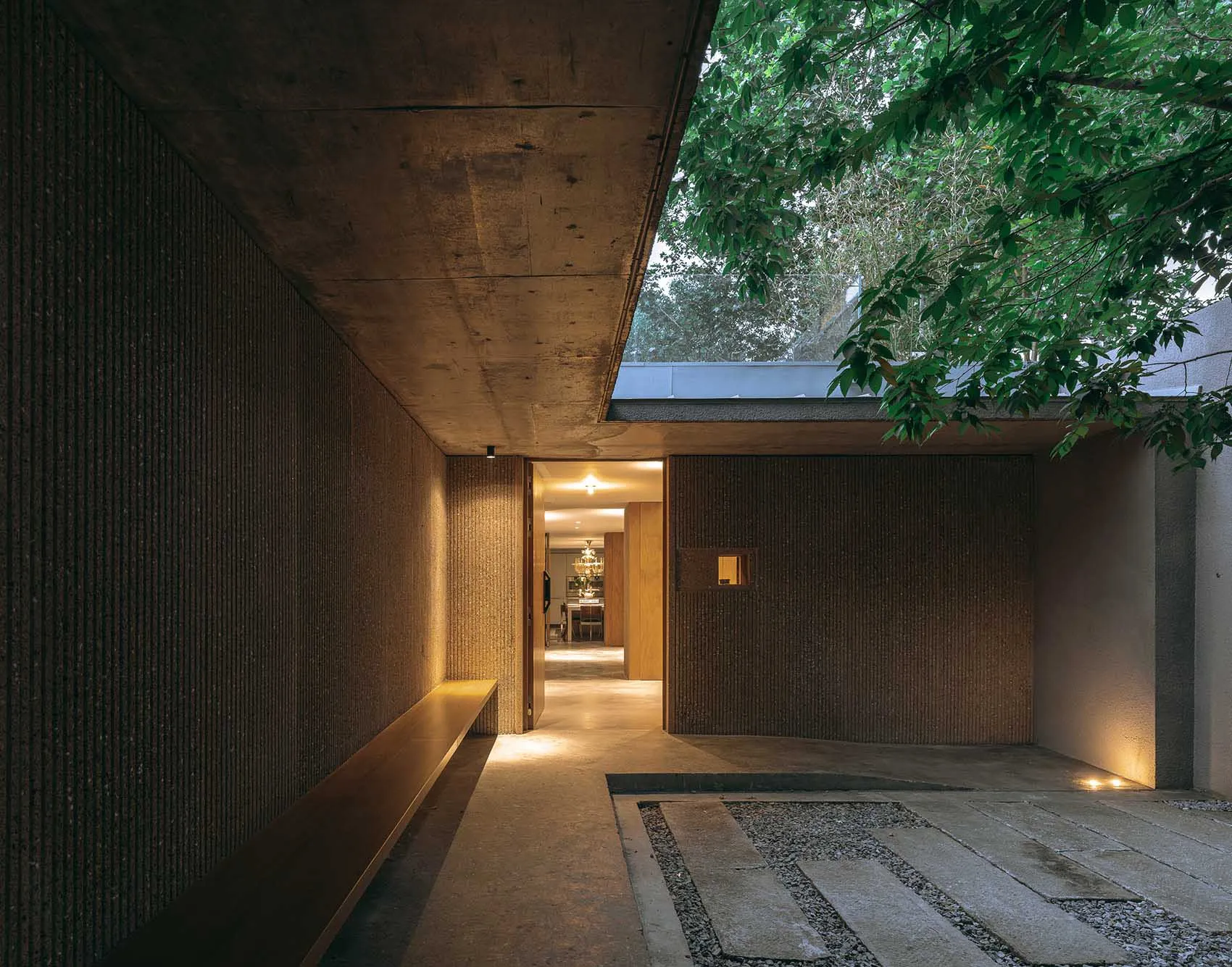Modern residential entrance featuring concrete walls and wooden bench.