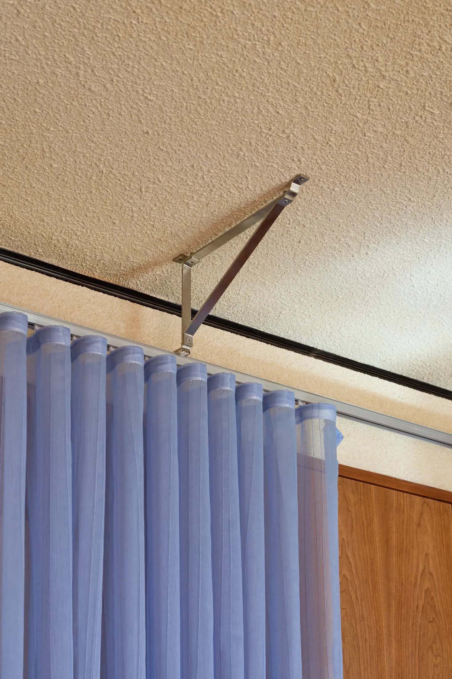 A shot of a hospital room showing a blue curtain hanging from a ceiling-mounted track system.