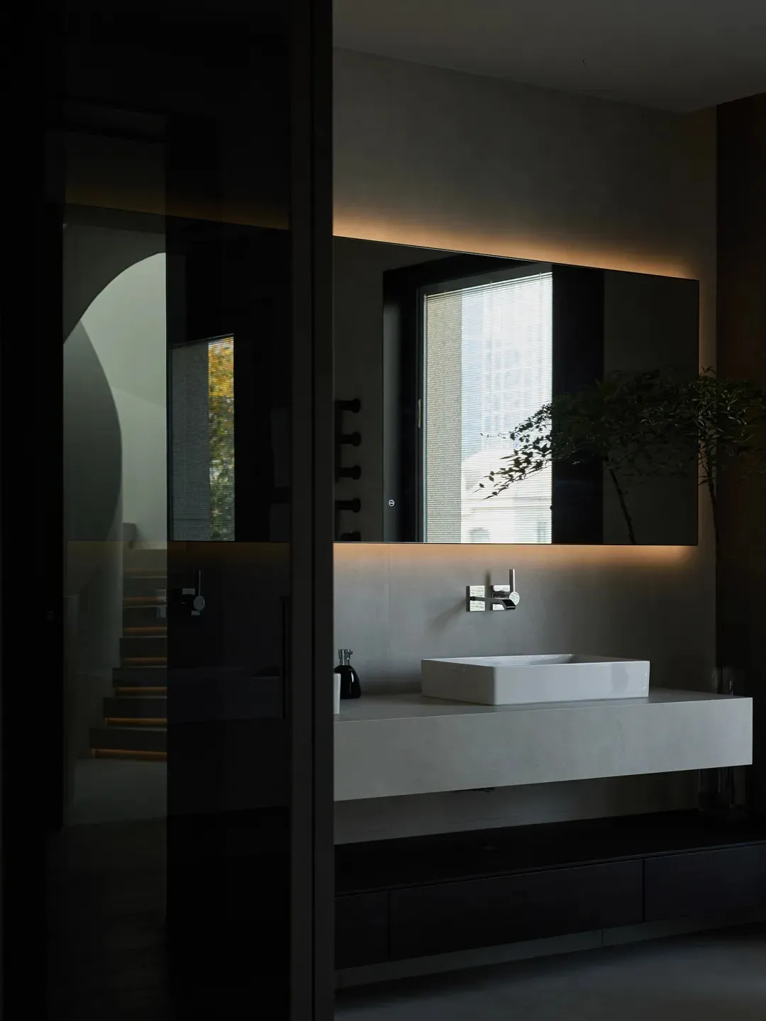 A modern bathroom featuring sleek, minimalist design with concrete elements and artistic installations.