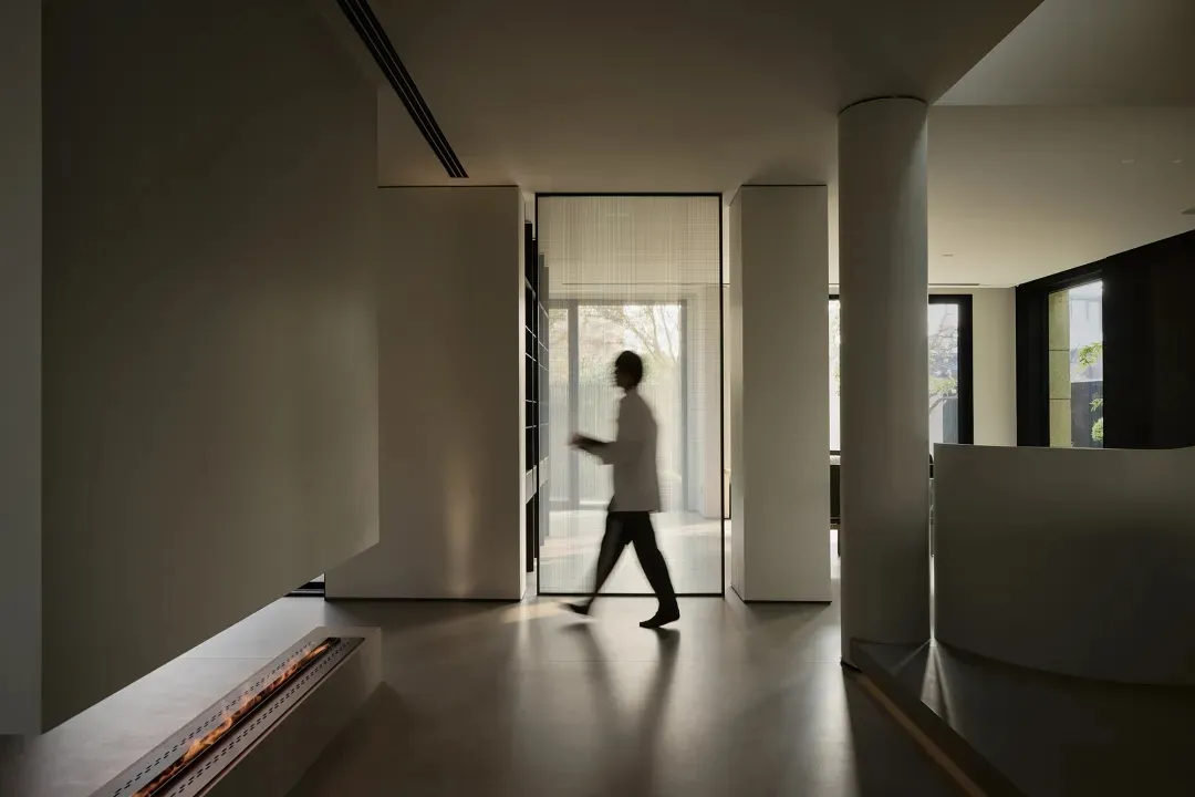 A modern minimalist interior space with a metallic fireplace and glass windows.