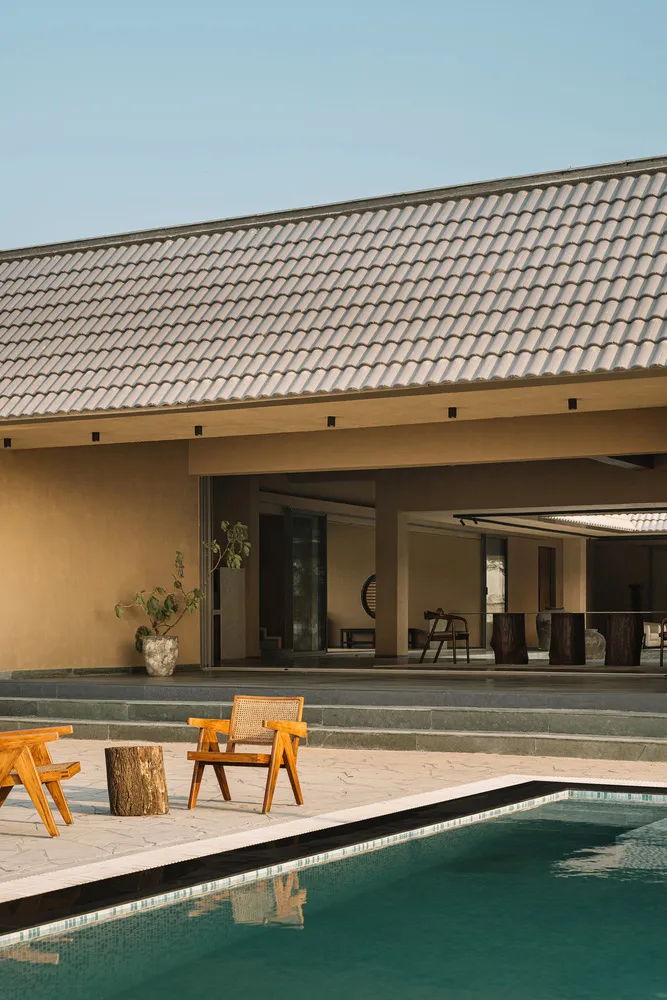 Outdoor residential area featuring a tiled roof, wooden furniture, and a swimming pool.