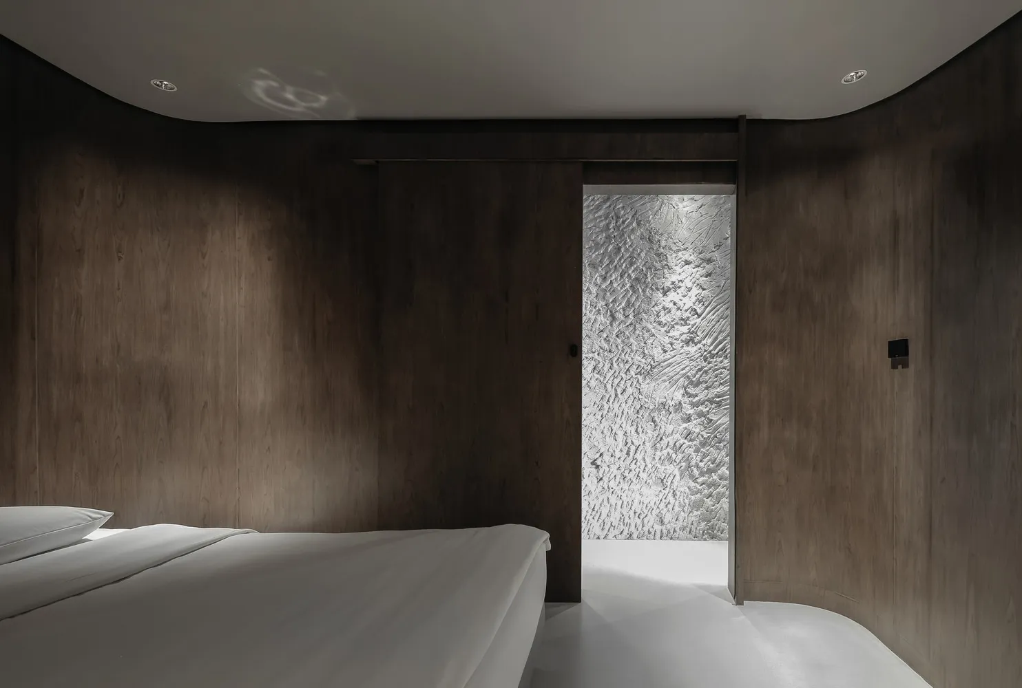 Minimalist bedroom with white bedspread and wooden panel walls