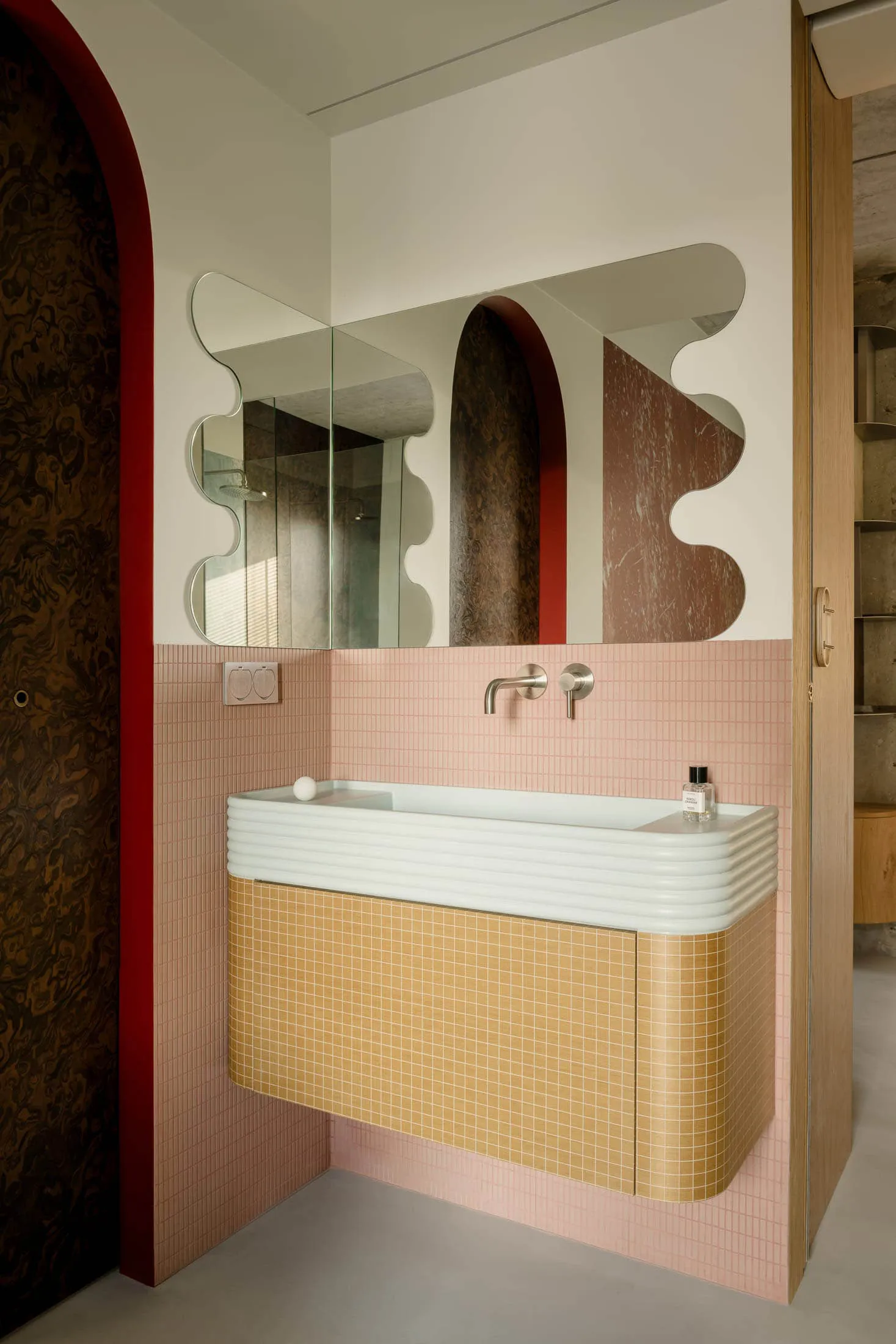 A modern bathroom featuring pink tiled walls, a floating vanity, and a sleek white countertop.