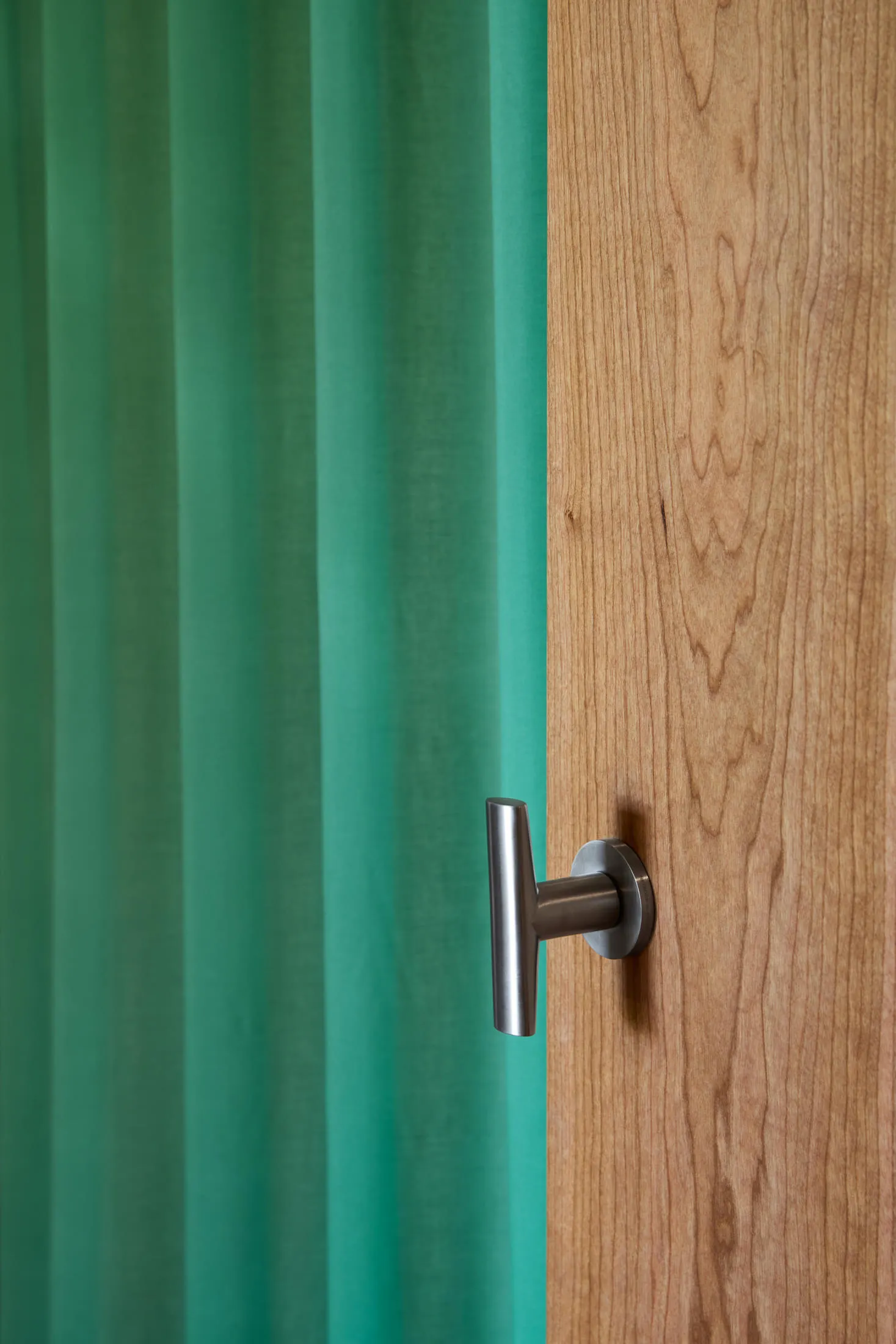 A modern interior with a wooden door and a turquoise curtain.