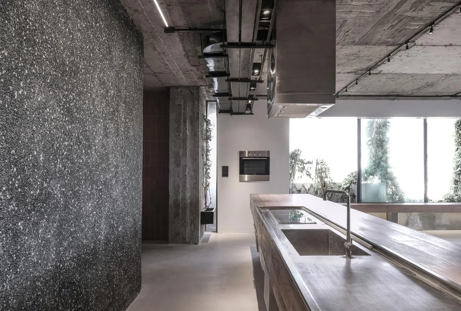 Modern kitchen with minimalist design, featuring a concrete countertop and a steel sink.