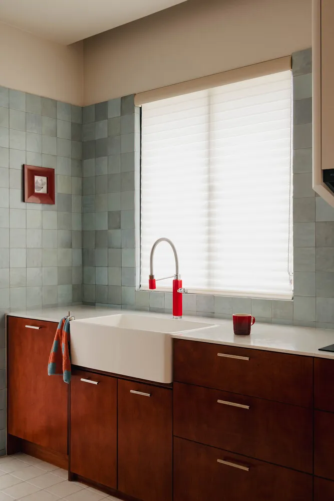 Modern kitchen featuring tile backsplash, concrete countertops, and wooden cabinets in front of a large window.