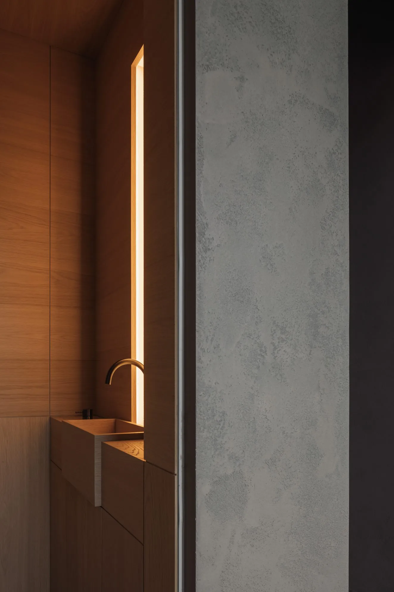 A minimalist bathroom with wooden panels and a window letting in natural light.