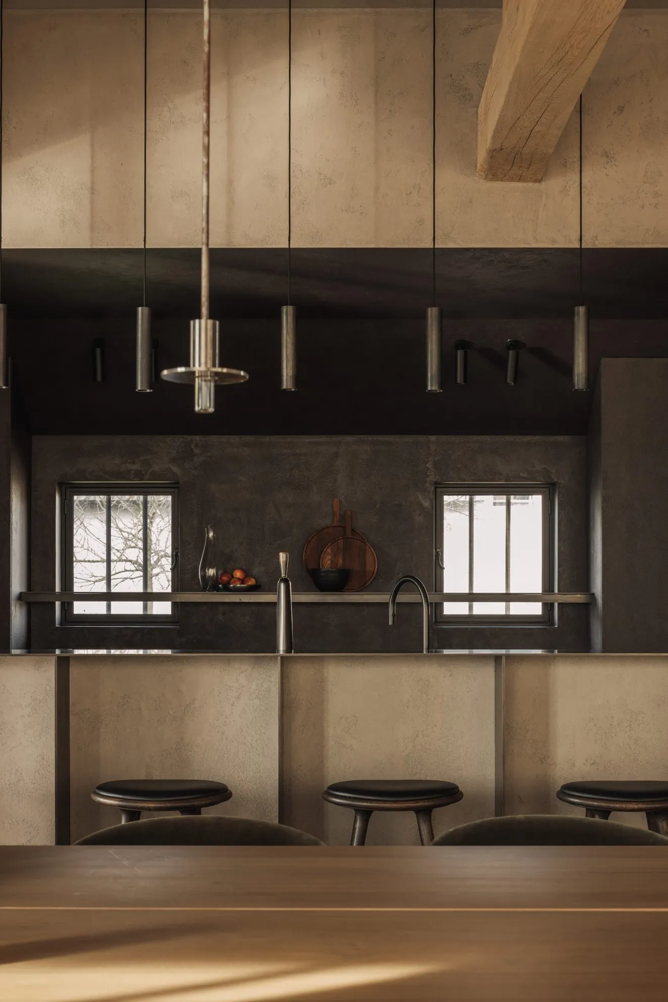 Industrial restaurant kitchen with metallic counter and stools.