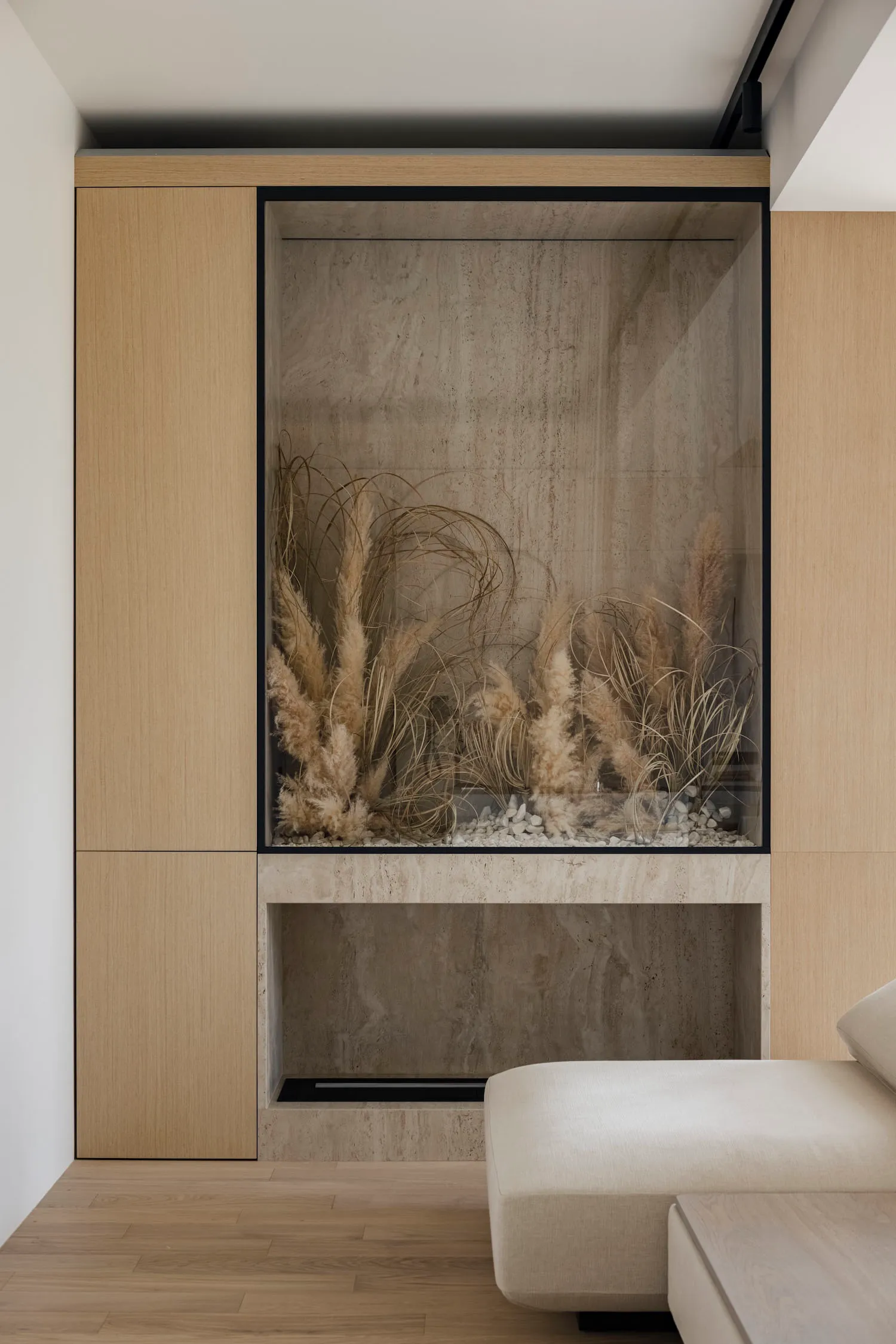 Modern minimalist living room featuring a fireplace with a slide design, wooden cabinetry, and shelves.