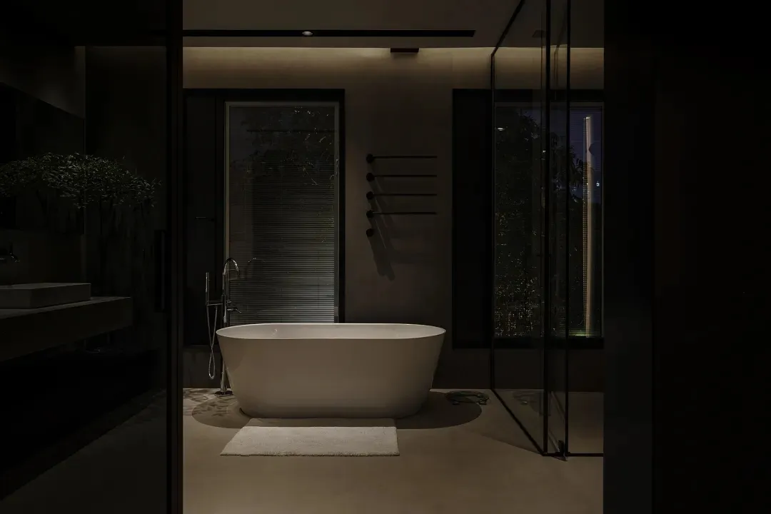 A modern bathroom with a freestanding bathtub, concrete floor, and large windows overlooking the outdoors.