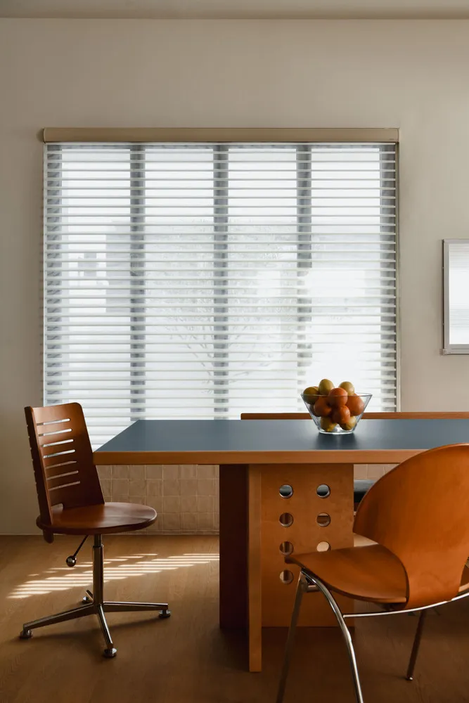 A modern dining room featuring minimalist design with wood furniture and blinds
