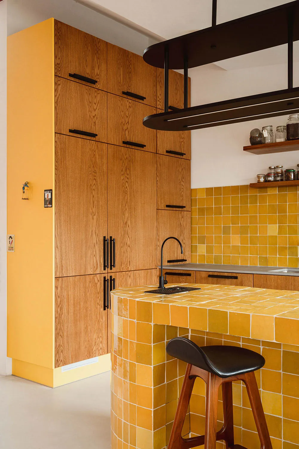 A modern kitchen featuring bright yellow square tiles on the walls and countertops.