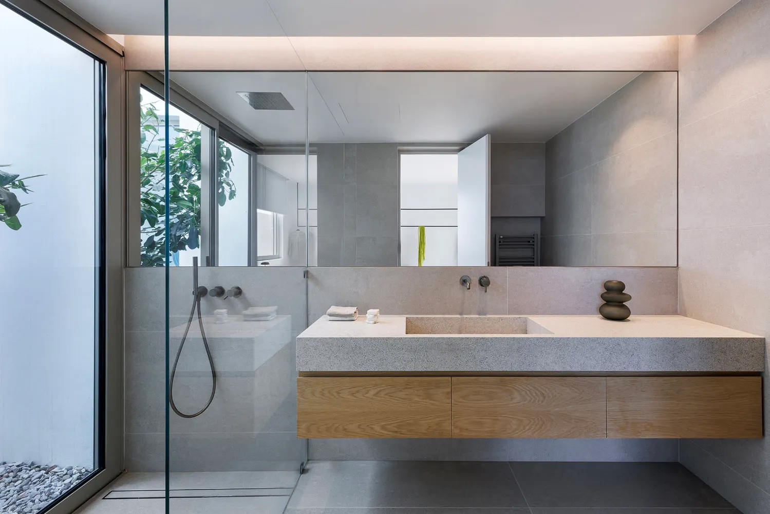 Modern minimalist bathroom with concrete sink and walls, glass shower enclosure, and large mirror.