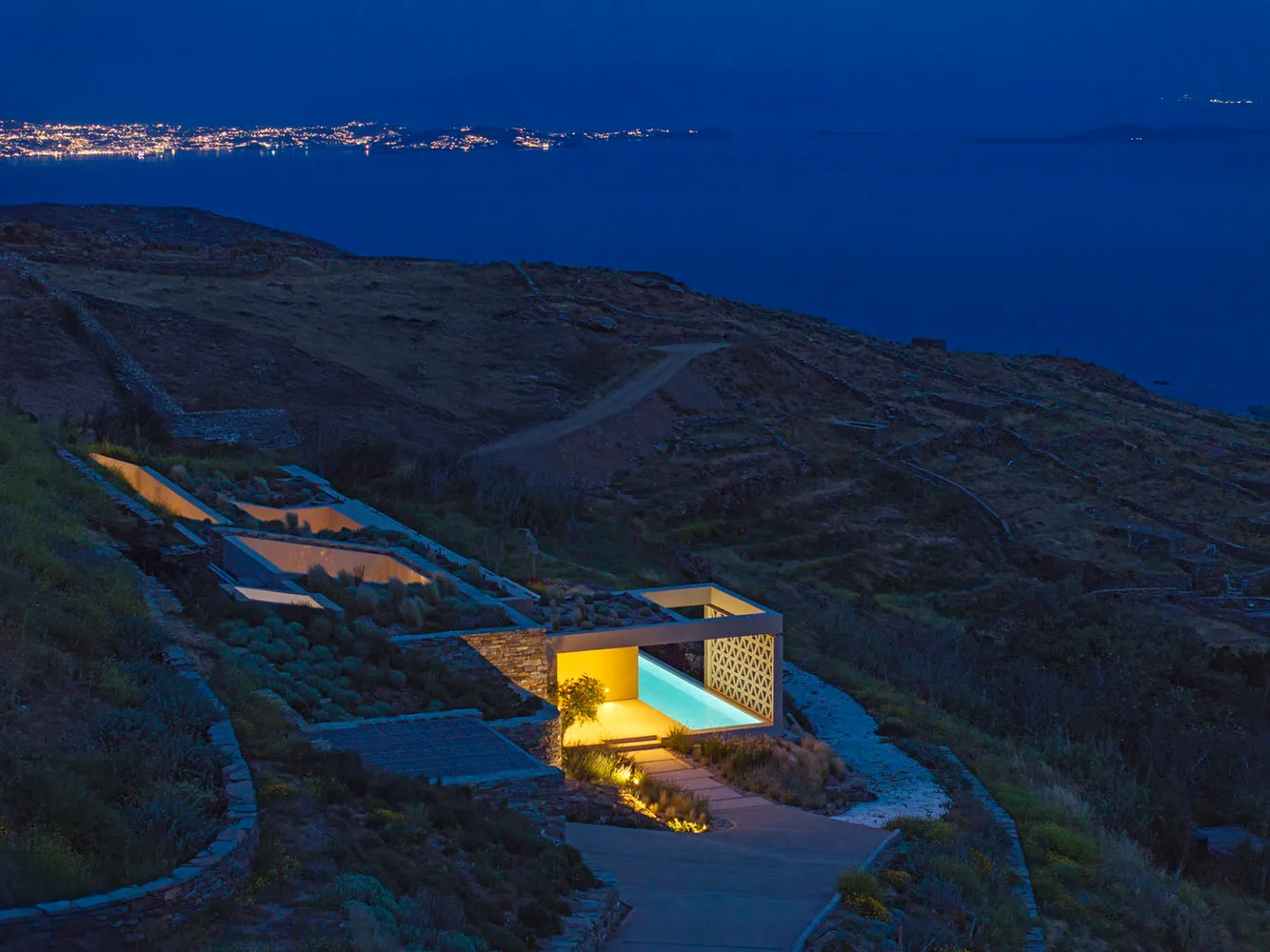 Modern residential architecture featuring concrete structures on a hilly landscape at night.